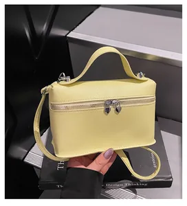 Nahaufnahme einer blassgelben Handtasche aus strukturiertem Leder mit Herz-Reißverschlüssen