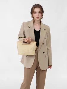 Fashionable woven straw handbag with a rectangular handle, styled on a model in a blazer