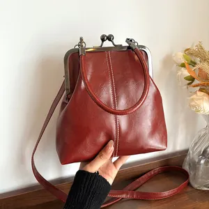 Vintage bordeauxrode schelp crossbody tas met een retro metalen sluiting en handvat