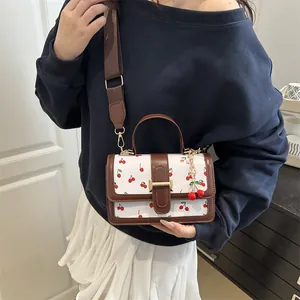 Cute cherry print crossbody bag with brown stitching and wide shoulder strap
