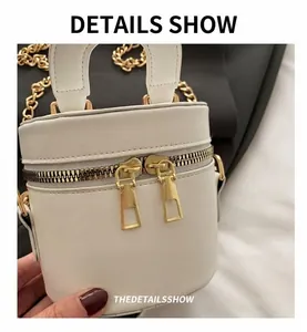 Nahaufnahme einer weißen Beuteltasche mit zwei goldenen Reißverschlüssen und Leder