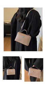 Detailansicht einer beigen Lederbox-Tasche mit dekorativen Herz-Reißverschlüssen.