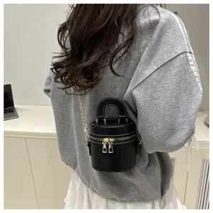 Schicke schwarze Mini-Beuteltasche mit goldener Kette, getragen von einem Modell.