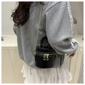 Stylische schwarze Beuteltasche mit goldener Kette, getragen von einem Modell