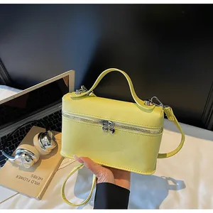 Nahaufnahme einer leuchtend gelben Box-Tasche aus strukturiertem Leder direkt in der Hand