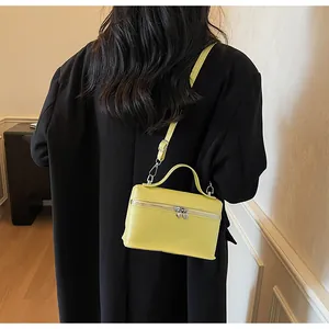 Elegante limonengelbe Mini-Umhängetasche getragen zu einem schwarzen Blazer in Innenräumen