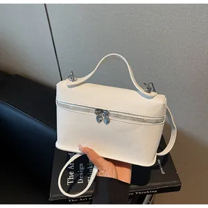 Makrodetail einer weißen Kunstlederhandtasche mit eleganten herzförmigen Doppelreißverschlüssen