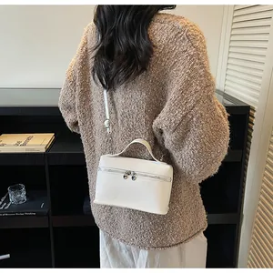Lifestyle-Foto einer weißen Mini-Umhängetasche mit herzförmigen Reißverschlüssen.