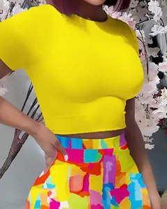 Detail view of yellow round neck crop top and colorful abstract print bodycon skirt set.