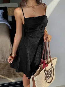 Dettaglio di un elegante mini abito nero con motivo floreale e spalline