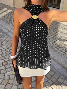 Close-up of a stylish black polka dot halter top featuring a gold metal neck detail