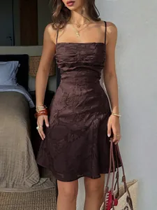 Dettaglio di un mini abito marrone strutturato con spalline sottili e tessuto jacquard.