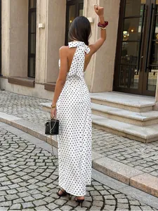 Back view of elegant white polka dot halter maxi dress with a large decorative bow.