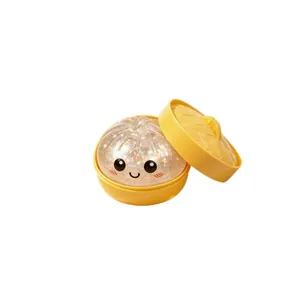 Glittery transparent Baozi squishy toy with cute smiley face in a yellow steamer container