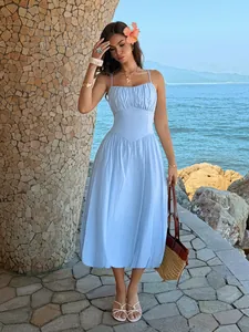 Hellblaues plissiertes Trägerkleid in tropischer Urlaubsatmosphäre am Meer präsentiert