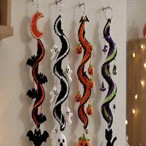 Detailaufnahme von vier bunten handgemachten Halloween-Häkelspiralen an einer weißen Wand.