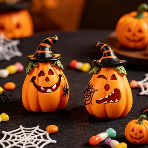 Detailed view of two resin Halloween pumpkin figurines wearing striped witch hats.