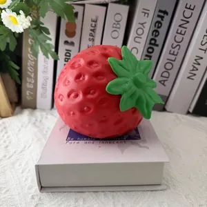 Close-up of oversized red strawberry squishy toy for stress relief on decorative book