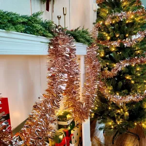 Rose gold Christmas tinsel garland draped on a white mantel and tree for festive home decor.