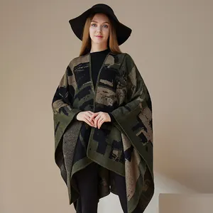 Donna che indossa un poncho in maglia a motivi etnici con cappello nero su sfondo beige