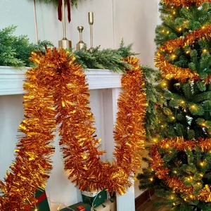 Close-up of sparkling orange tinsel garland draped on a white mantel for Christmas decor.