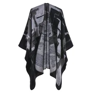 Vista dettagliata del poncho in maglia grigio e nero con motivi etnici astratti ora