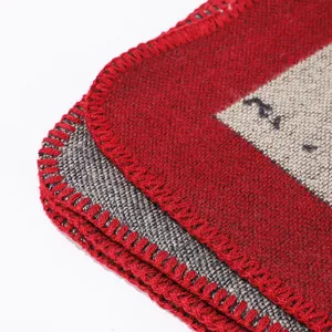 Dettaglio macro del bordo rosso a punto coperta di uno scialle poncho etnico