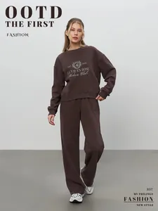 Full body view of a woman in a brown embroidered sweatshirt and wide leg pants set