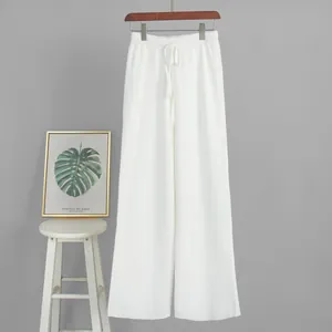Detailed view of white knitted wide-leg trousers featuring an adjustable drawstring waist.