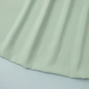 Détail macro du tissu de jupe plissée vert menthe montrant le drapé et la texture