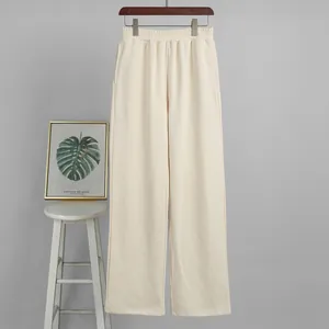 High-waist off-white wide-leg sweatpants hanging against a neutral gray background wall