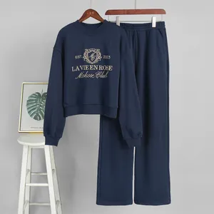 Detailed view of navy blue two-piece lounge set with gold embroidered sweatshirt and pants