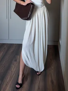 Détail d'une jupe longue plissée blanche avec fente latérale et tissu fluide léger