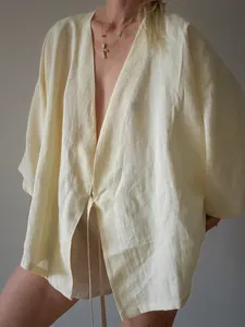 Detailweergave van het ademende lichtgele kimono-overhemd met linnen look en strik.