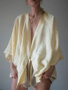 Detail van een ademend geel linnen kimono vest met een V-hals en een striksluiting