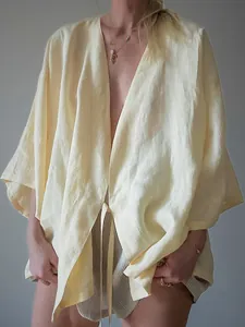 Detail van een losse linnen kimono vest met strikceintuur in lichtgele afwerking