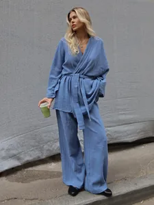 Female model wearing a blue cotton wrap pajama set with wide-leg pants in gray wall background