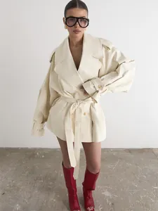 Close-up detail of the cream-colored double-breasted trench coat featuring a stylish belt