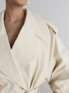 Close-up detail view of elegant beige double-breasted trench coat lapel and shoulder