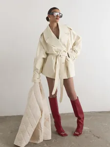 Fashionable cream double-breasted trench coat with belt shown on model with red boots
