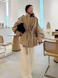 Chic street style khaki trench coat with waist belt shown in a modern interior boutique