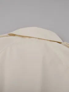 Detailed macro view of off-white trench coat collar and epaulette with fine stitching.
