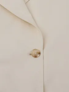 Macro view of a marbled button on a classic beige trench coat with fine stitching