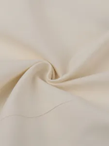 Close-up detail of high-quality off-white twill fabric on fashion trench coat
