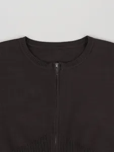 Detalle del top de punto marrón oscuro con cremallera metálica y cintura acanalada.
