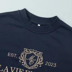 Close-up of gold embroidery and crest on navy blue sweatshirt neckline