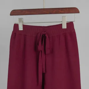 Close-up detail of burgundy knitted trousers featuring a ribbed drawstring waistband