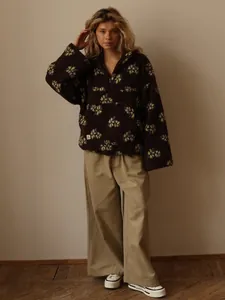 Full view of woman in dark brown floral fleece pullover and khaki wide-leg trousers