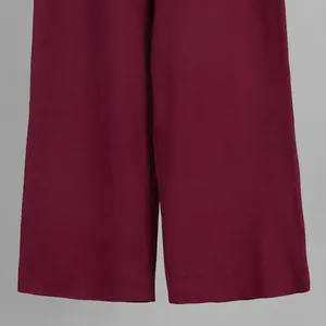 Detail view of burgundy ribbed knit wide-leg trousers showing soft fabric texture