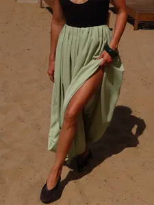 Vue détaillée d'une jupe longue plissée vert sauge avec fente haute sur la plage